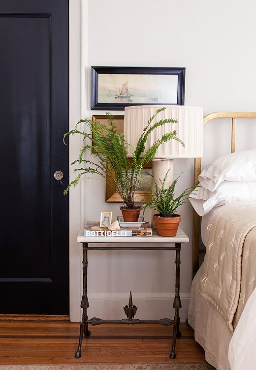 Smith prefers to paint doors what she calls “noncolors” such as black or taupe rather than white. In the guest bedroom the black door adds a masculine edge to an antique brass bed and marble table.

