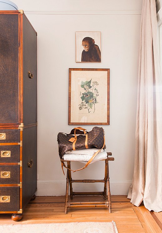 A small empty corner of the guest room becomes highly functional with the addition of a stool-cum-luggage rack. The tight palette helps make vintage finds, like the monkey painting and the Audubon print, look cohesive.
