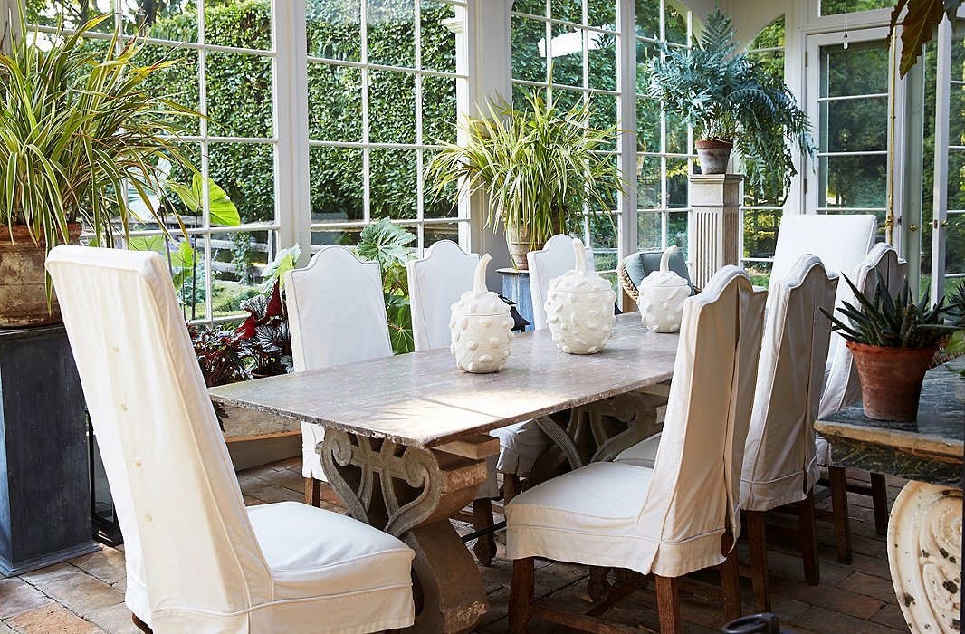 The very sociable Bunny and John host many dinner parties in the conservatory. The tabletop and the bases are made of stone; the ceramic gourds are by Christopher Spitzmiller.

