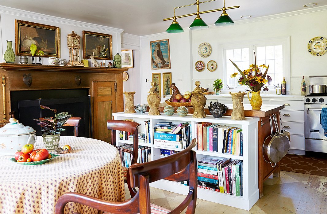 The kitchen features modern appliances alongside the house’s original 18th-century fireplace; the “tree trunk” pottery pieces atop the bookcase are antique.

