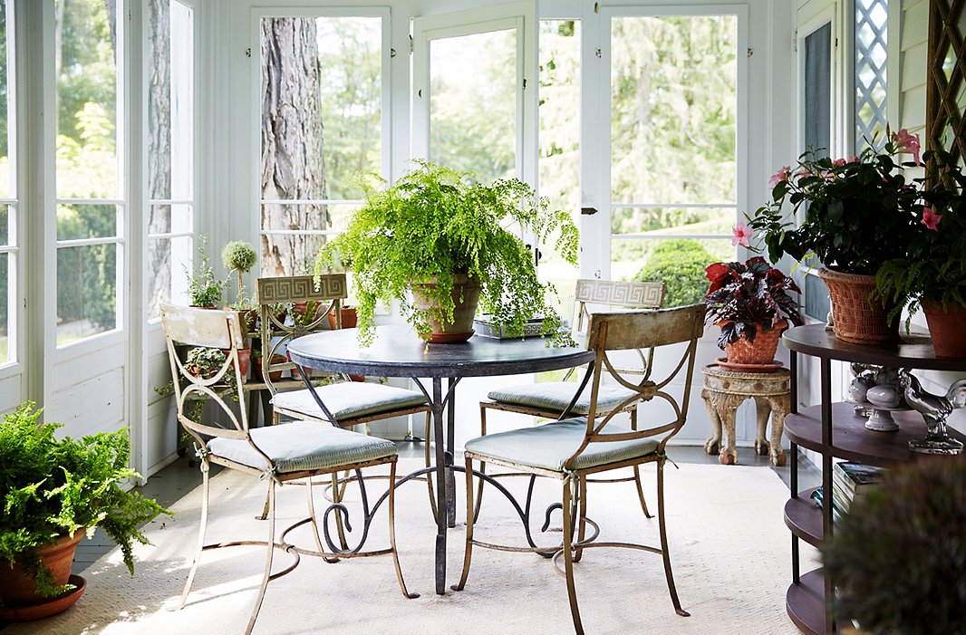 A slightly worn table and set of chairs are perfectly at home on the porch. “I don’t want to go in a room where everything needs restoring,” says Bunny. “But there is something about patina that is relaxing.” The washable rugs are from her collection for Dash & Albert.
