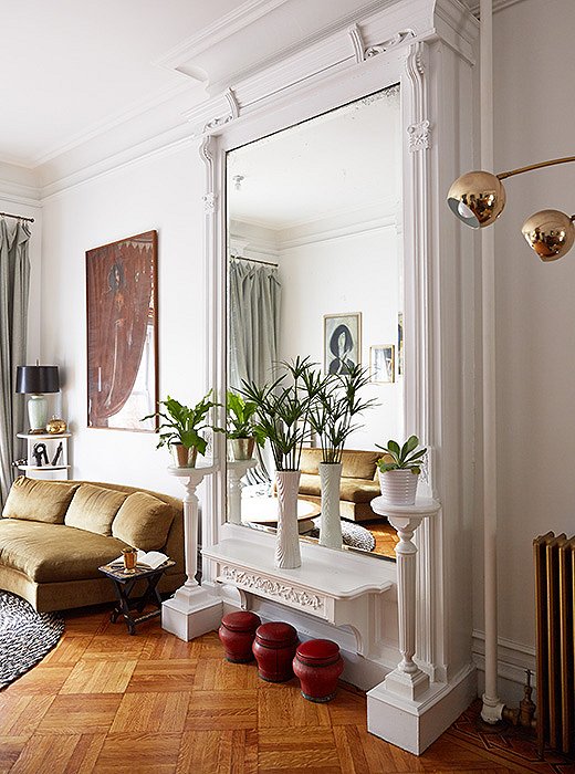 White paint accentuates the pillars and other architectural forms around a monumental mirror.
