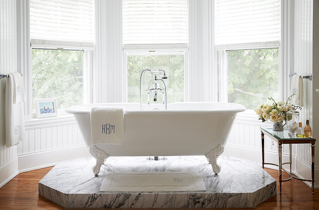 “I wainscoted the walls, had the whole room painted with Ralph Lauren’s Brilliant White, and designed a Carrara marble platform so the new claw-foot Cheviot tub would have a perfect-height view of the pool gardens,” says Delaney of her master bath revamp.
