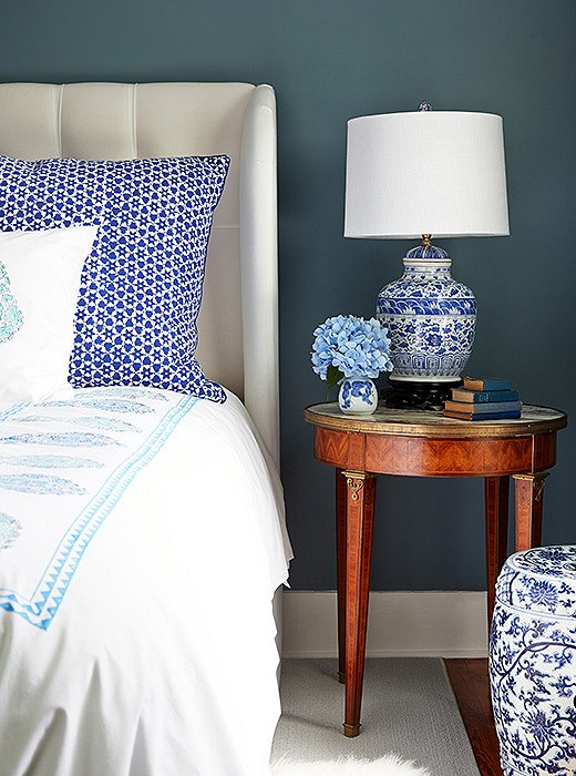 “I love a blue-and-white color palette and mixing and matching patterns and textures,” says Delaney. Nowhere is that more evident than by her bedside, where a chinoiserie garden stool and lamp live in harmony with a mix of brightly printed Indian bedding.
