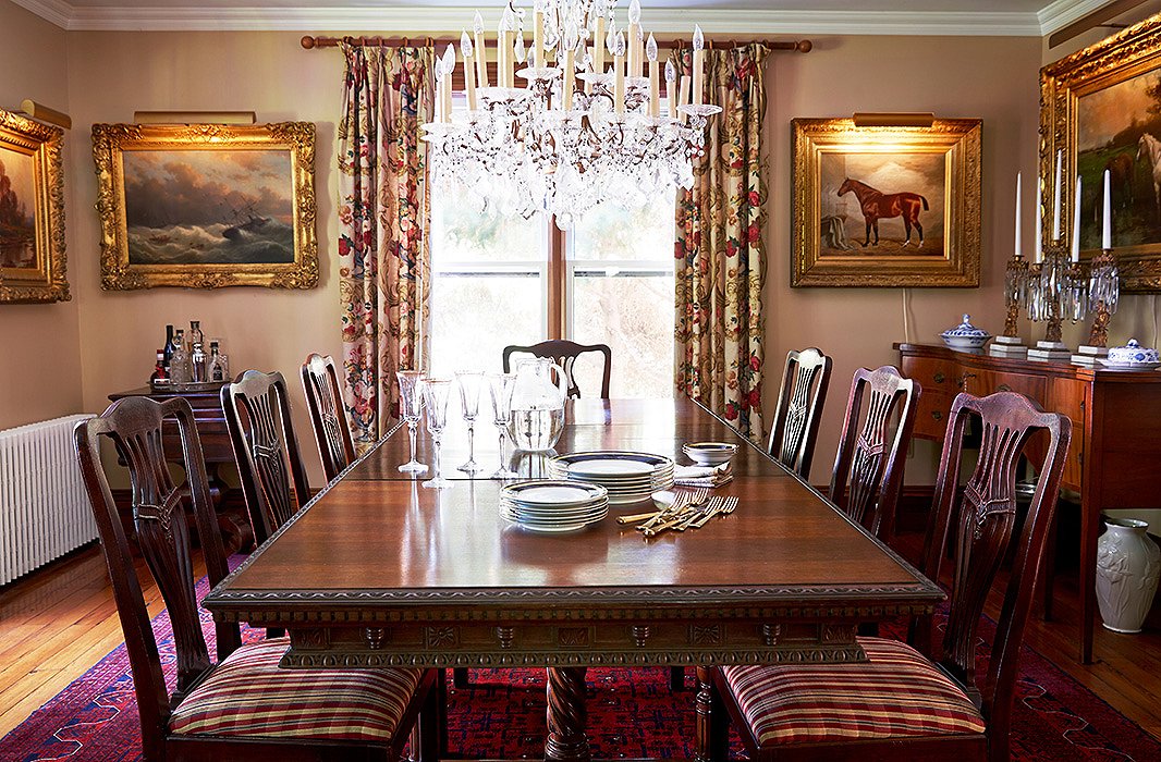 The sunlit dining room is decorated in warm tones and textures, from the Edwardian dining table to the Persian rug to the dining chairs upholstered in a Ralph Lauren tartan. A 19th-century Czech crystal chandelier presides over the scene.
