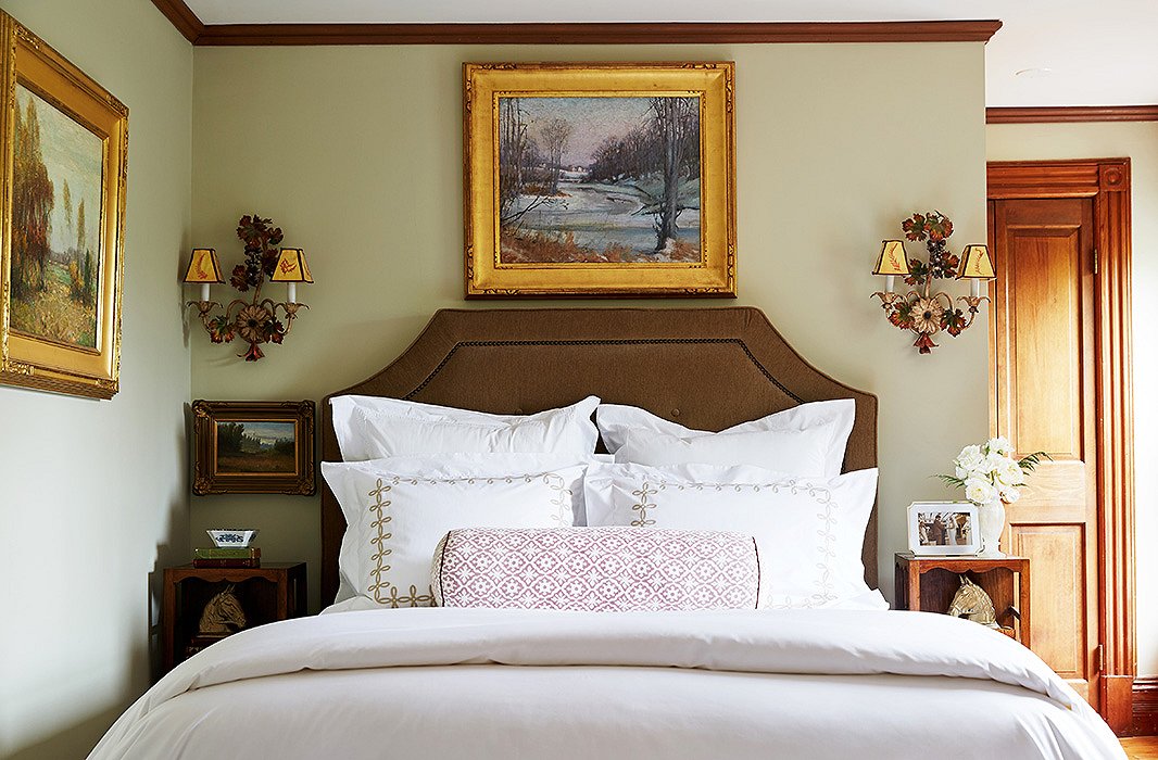 In a guest bedroom, Delaney again favors symmetry, flanking a custom-upholstered linen headboard with a pair of Italianate sconces. Sumptuous bedding by Matouk and Yves Delorme makes for an inviting place of rest.
