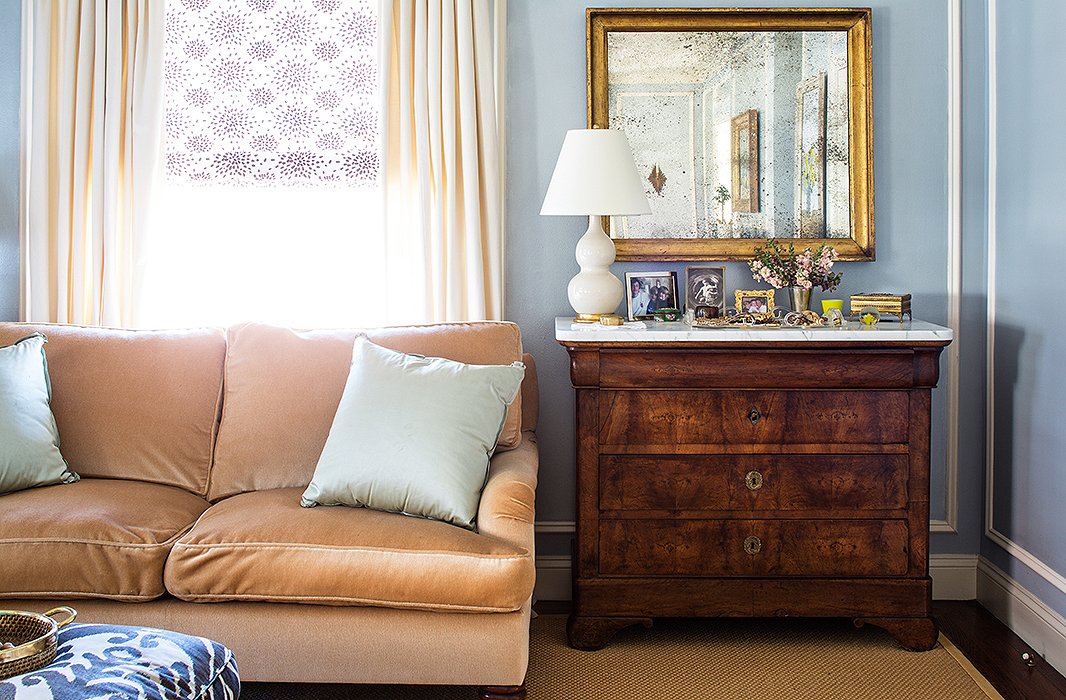 Subtle splashes of pattern—in the form of the lilac window shade and the blue footstool—enliven a purposefully pale palette.
