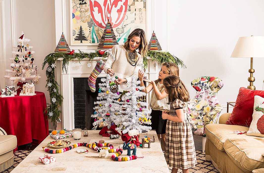 On a table next to the mantel, the girls’ finished mini trees are used to create a charming holiday scene, complete with festive ceramic houses.
