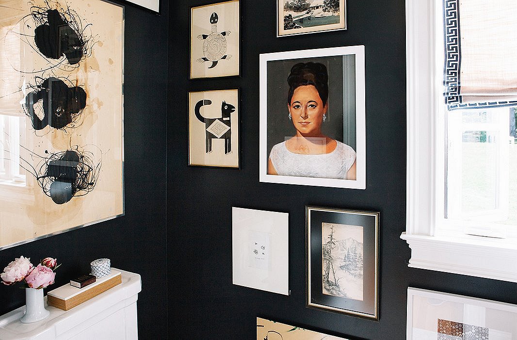 The ground-floor bathroom is painted black, to echo the all-black upper floor. A dramatic Cuban portrait stands out on the otherwise black-and-white gallery wall.
