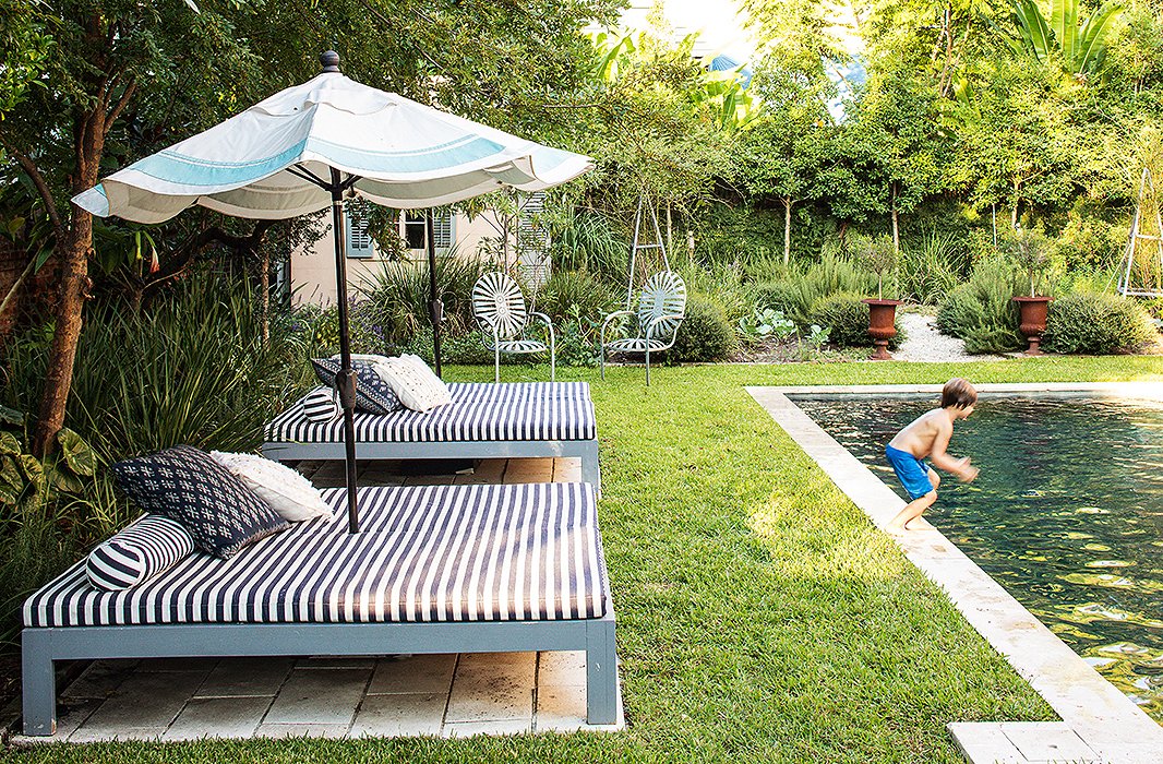 Young Ruffin prepares for a plunge into the backyard’s saltwater pool. The pool beds and umbrella were custom-made, and the metal chairs are vintage.
