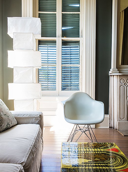 In the bedroom seating area, the gleaming white Eames chair and Noguchi lamp echo the bed’s pale geometry and modern feel. A Fornasetti table adds a bit of color.
