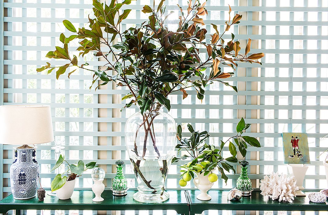Hand-me-down console tables are topped by more hand-me-downs, accented by bouquets of magnolia branches and Meyer lemons clipped from trees in the backyard.
