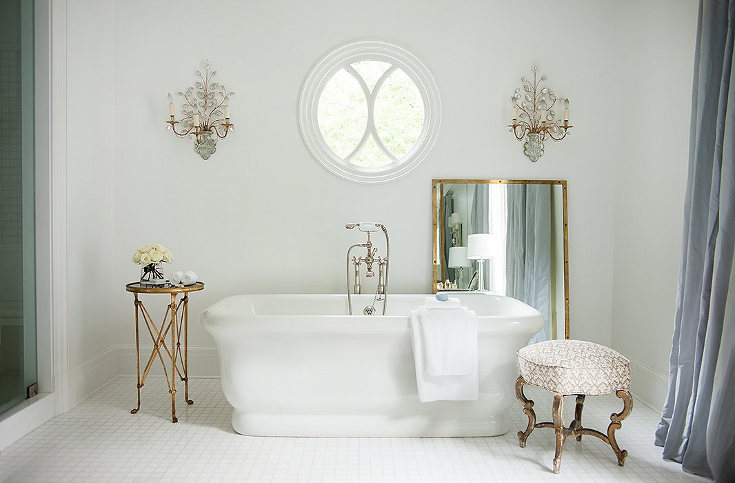 Designer Suzanne Kasler chose curtains in a soft gray-blue silk for her dreamy master bathroom. The cool tone sets off the warm antique-brass finishes and adds to the restful atmosphere. Photo by Erica George-Dines.
