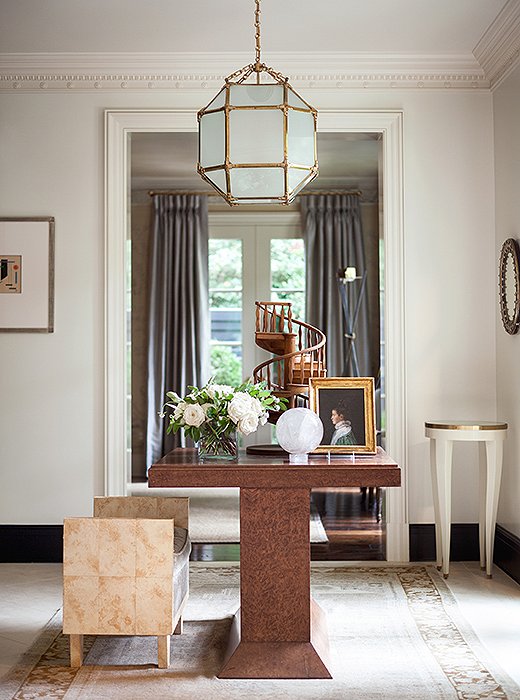 Below a 1940s French lantern, a burl-wood table anchors the light-filled entryway. Suzanne painted the baseboards a dark charcoal to define the architectural space.<br />