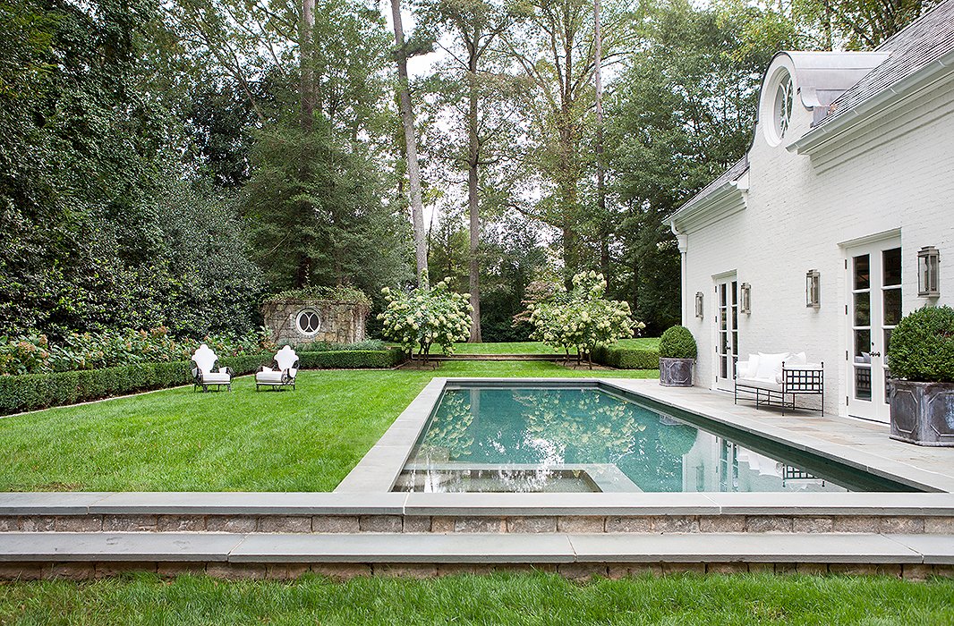 In the backyard, boxwoods in clean, classic shapes complement the home’s Regency-style exterior. Suzanne found the vintage wrought-iron armchairs at a flea market in Avignon, France.
