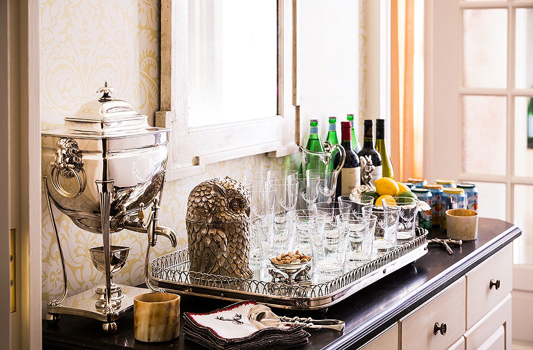 Just off the kitchen, a self-serve bar set with an antique tray, thin glassware, and a silver coffee service that belonged to Alessandra’s grandmother helps relieve bartending duties. The quirky owl ice bucket is a visual pun on Alessandra’s family name, which means “little owl.”
