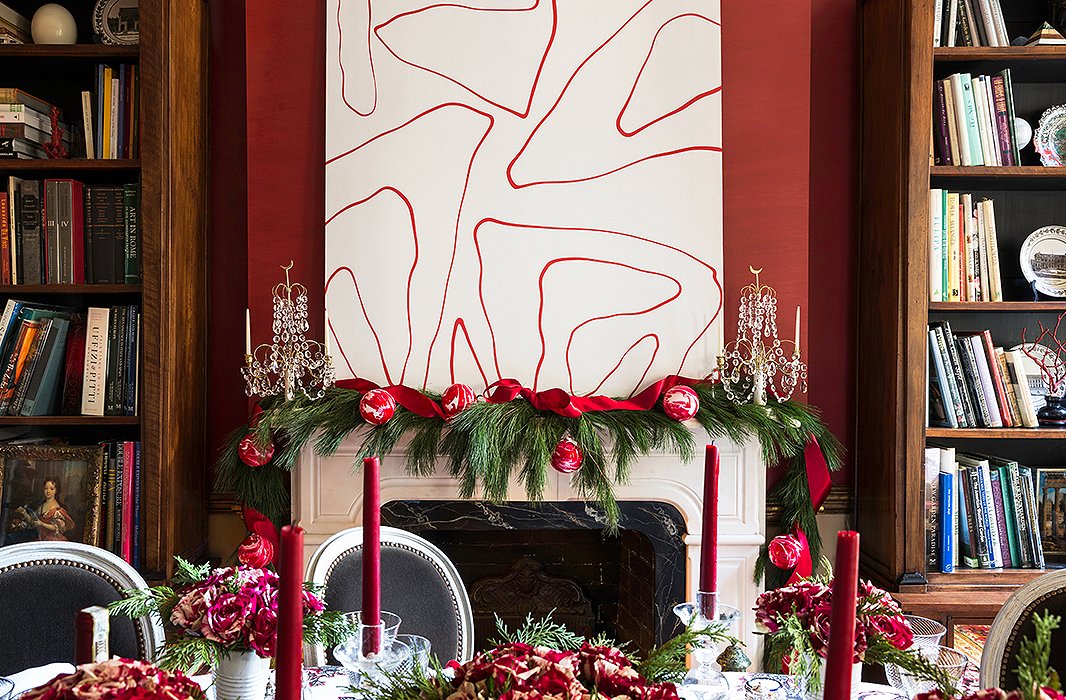 A 1970s abstract painting offsets the Victorian mantel, which Alessandra dresses up with a simple full garland. For “just a tiny bit of bling,” 18th-century Swedish candelabras do the trick, while red tapers bring the soft glimmer she loves. “My dining room at night is all candlelit.”
