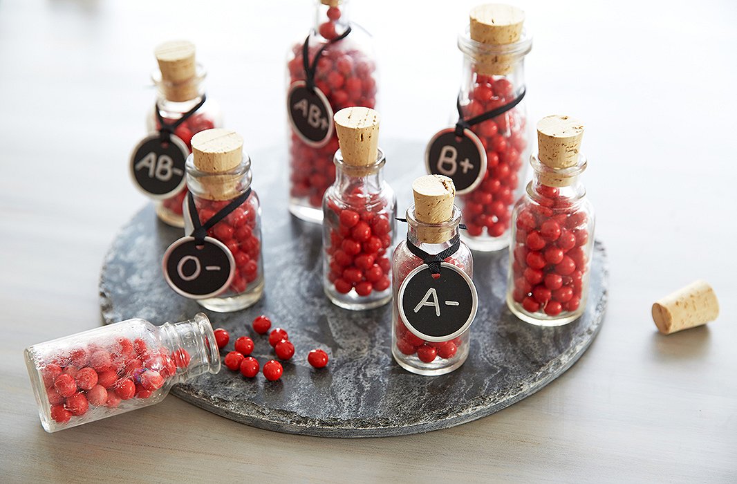 Mini corked apothecary bottles filled with tiny red candy balls mimic blood vials for simple and fun favors.
