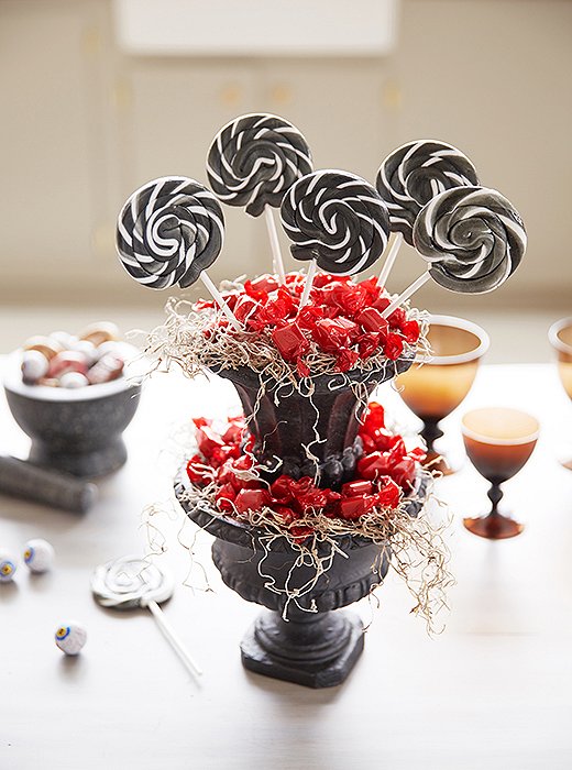 Stacked urns overflowing with sweets in red, white, and black make a showstopping lollipop display.
