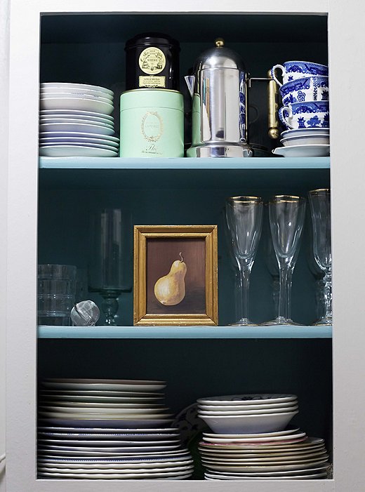 No canned soup here—a modernist coffee pot, a Ladurée tea box, and gold-rimmed champagne flutes fill one of the kitchen cupboards.
