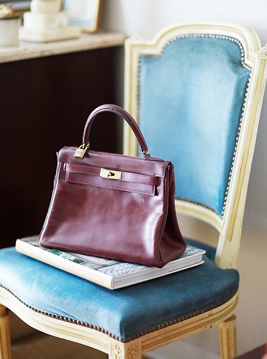 An Hermès bag perched on a French side chair. Upholstered in sky-blue velvet, the chair looks airy during the warm months and cozy in the winter. 
