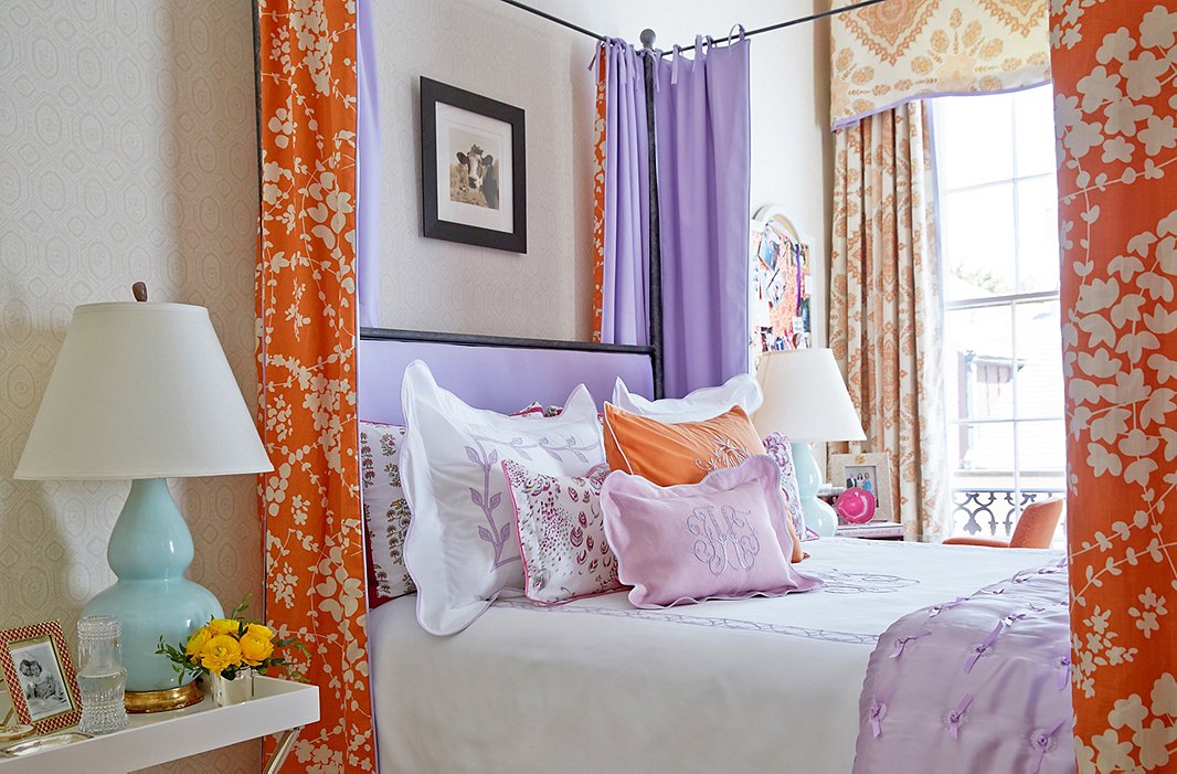 Linens and drapery in orange and lavender make for a dreamy guest bed.
