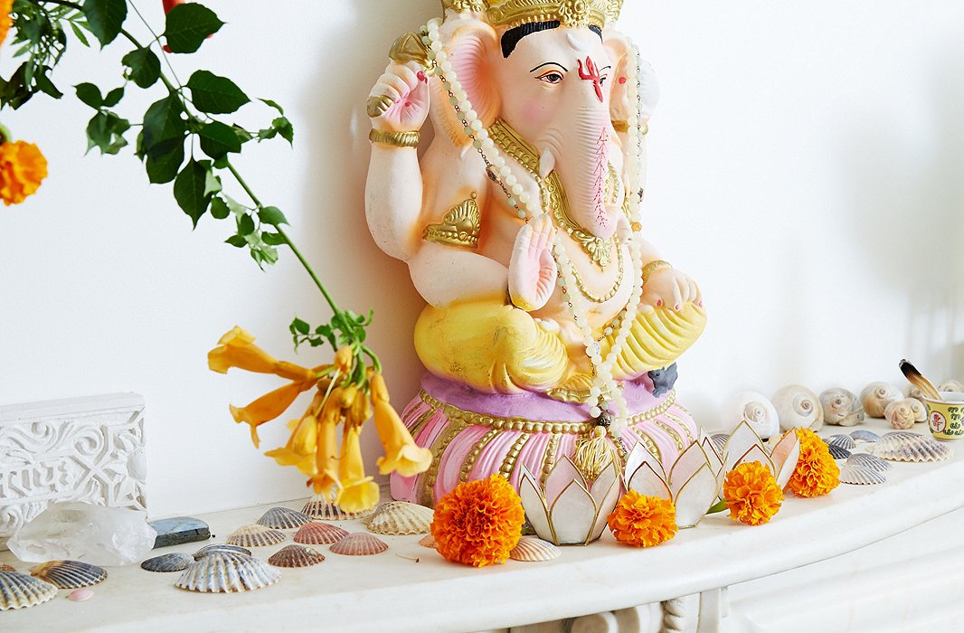 A Ganesha—a beloved Hindu deity believed to remove obstacles—sits over orange marigolds and scallop shells on Kelly’s mantelpiece.
