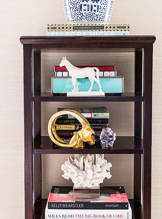 In an étagère, the striking objets—a brass ram’s head, a heroic white horse, a bold white coral—more than hold their own among the books.
