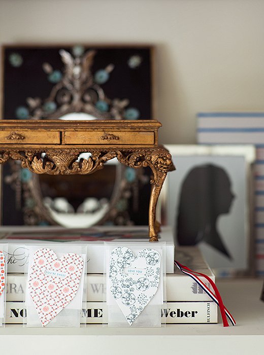 A miniature gilded desk, part of a larger collection of model furnishings, sits atop a stack of books in the bedroom. The silhouette was made in Paris and depicts Suzanne’s daughter, who gave her the two heart-shape cards.
