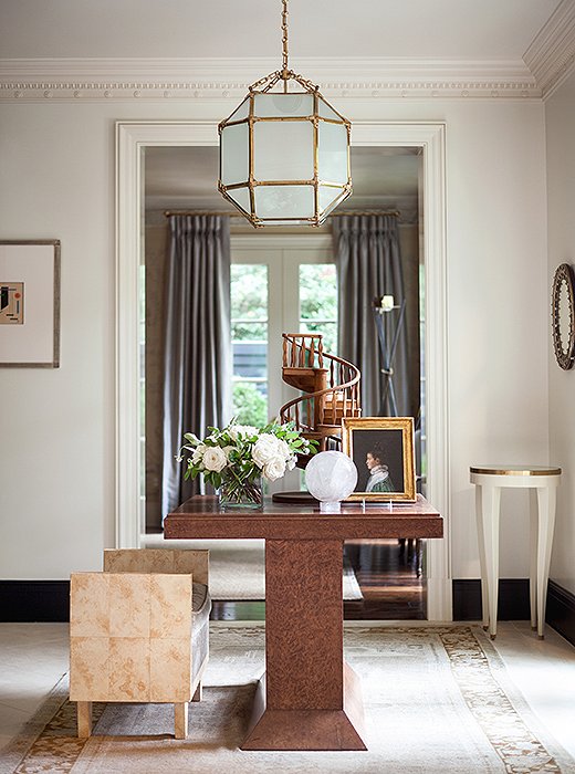 Below a 1940s French lantern, a burl-wood table anchors the light-filled entryway. Suzanne painted the baseboards a dark charcoal to define the architectural space.
