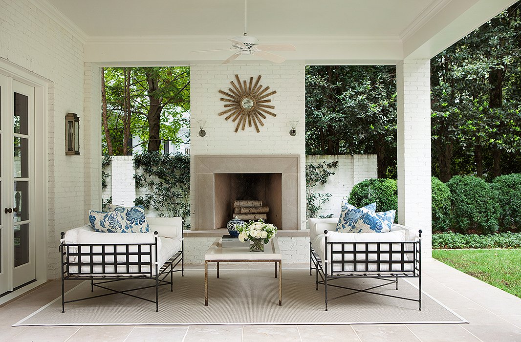 “I love having a house that interacts with the outdoors,” Suzanne says. On the terrace, the furniture’s strong lines play nicely off the sunburst mirror and round boxwood hedges.
