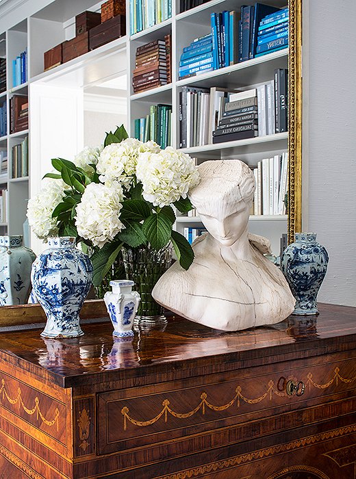 A substantial bust offsets ornate chinoiserie vases and intricate marquetry motifs for a balanced effect.
