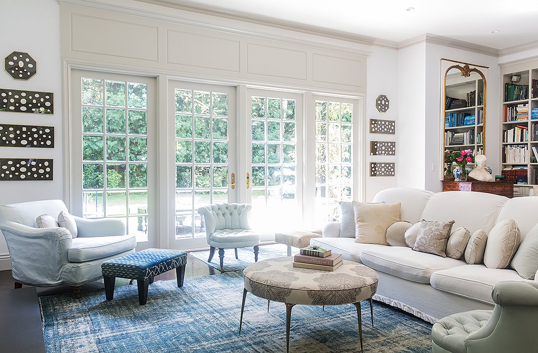 The living space in Windsor’s home is anchored in a blue-and-white palette that feels light and modern, thanks to a faded overdyed rug and crisp upholstery. Pale sage chairs add to the soothing ambience.
