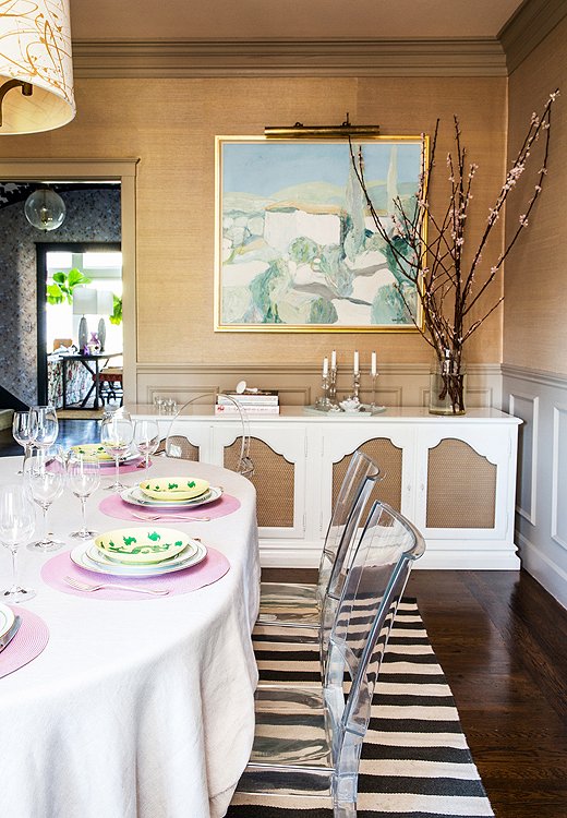 In a dining room made formal by grasscloth walls, a vintage white sideboard, and a painting by Roger Mühl, Lucite chairs are a welcome breath of modern whimsy. “They were affordable and wipeable,” says Chloe. “Sometimes at the end of a project when you have small kids, bulletproof is all that matters.”

