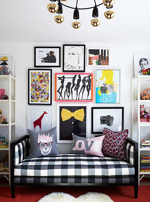 The room has a playful symmetry, centered on a black-and-white gingham daybed and a graphic gallery wall.
