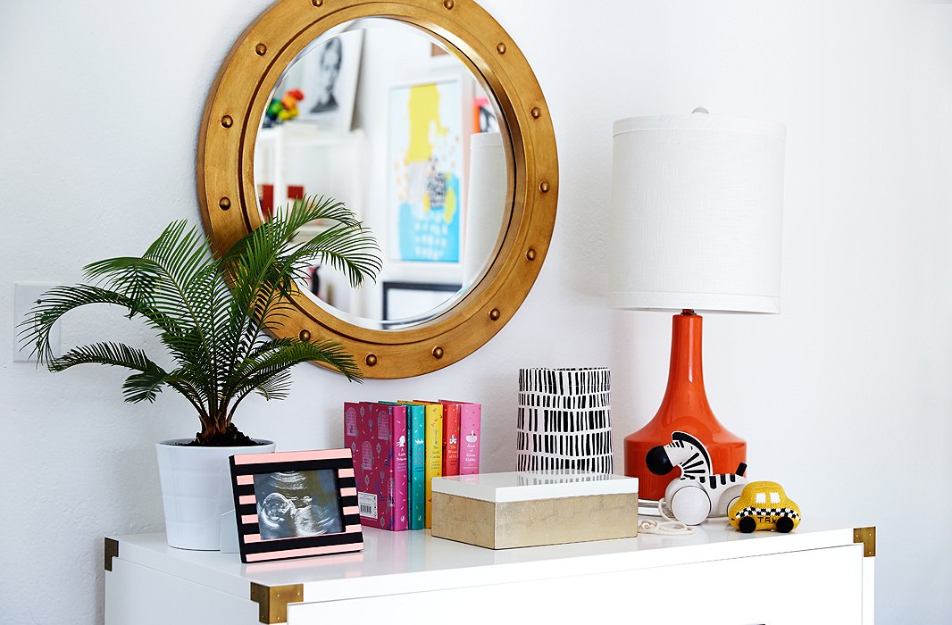 A white Campaign dresser with brass fixtures sets a chic tone and nods to tradition. At 42 inches wide, it easily accommodates a 30-inch changing tray on top, with plenty of room left for a punchy red lamp.
