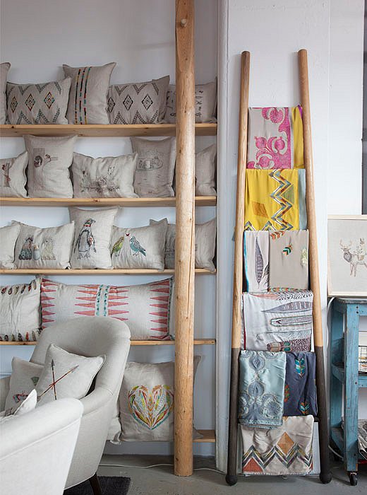 Embroidered linens and pillows hang out on built-in shelves made from horse-rail fencing by carpenter Tim Miller.
