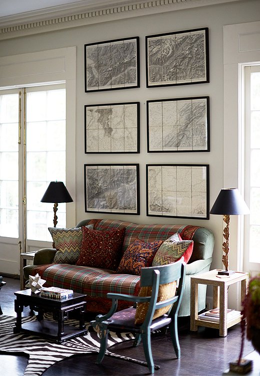 Of the living room’s various seating options, this blanket-covered love seat, tucked under a second set of Napoleon’s maps, is the “throne” of their harlequin Great Dane, India. “We keep a lint roller next to it at all times,” says Ross.
