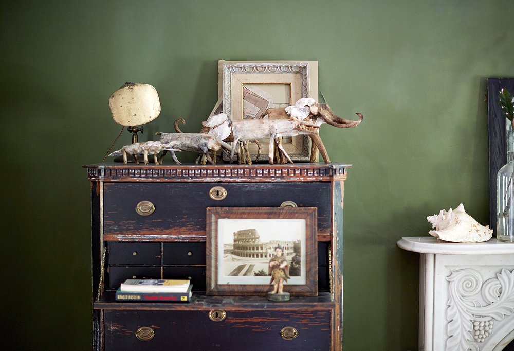 Folk-art animals made from husks, seeds, and shells by a man from North Fork, NY, march across the top of the duo’s antique secretary.
