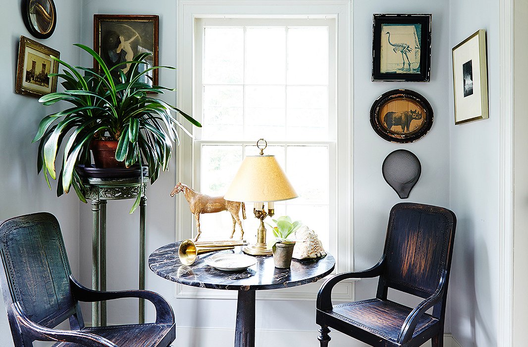 Dutch Colonial chairs from South Africa, an antique marble-top table joined to a cast-iron base, and art in weathered frames share a handsome patina.
