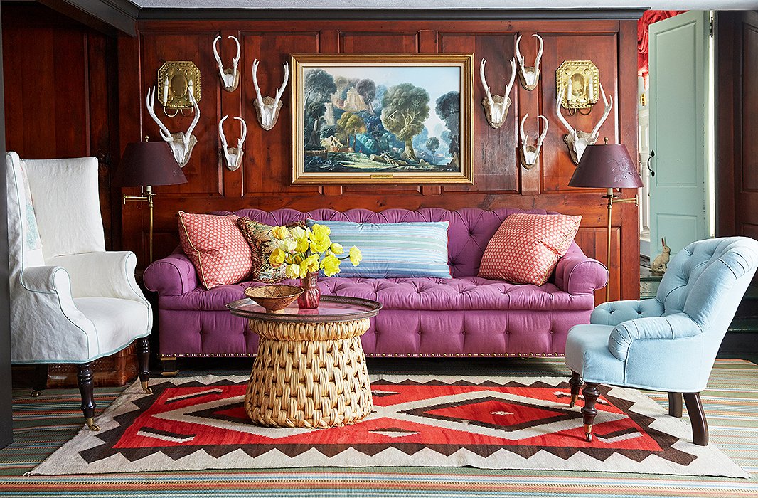 A theme running throughout the house, antlers stand out in stark relief from pine paneling. Jeffrey’s own designs (the sofa and the armchairs), a 19th-century French tole tray on a raffia table, and Native American carpets round out the eclectic mix.
