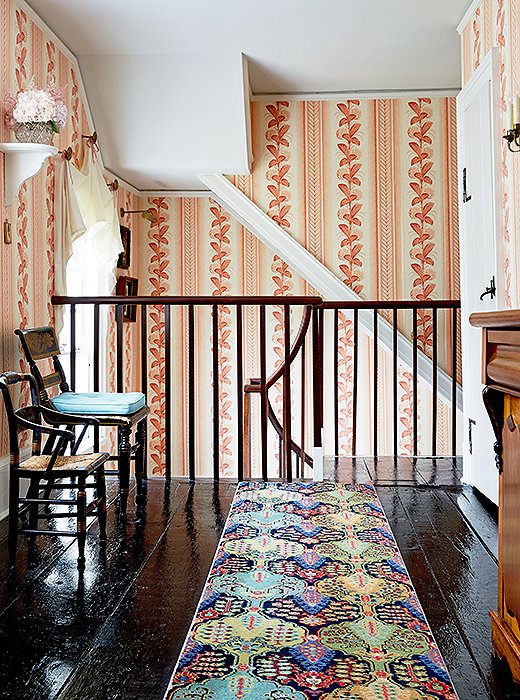 Follow the hydrangea wallpaper upstairs and you’ll find a wool Persian-style runner protecting black-painted pine floors.
