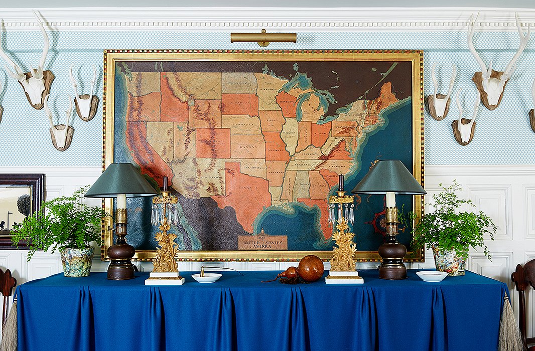 In the entrance hall, antlers collected over the years and a pair of 19th-century gilded metal oil lamps converted to electricity flank a vintage map.
