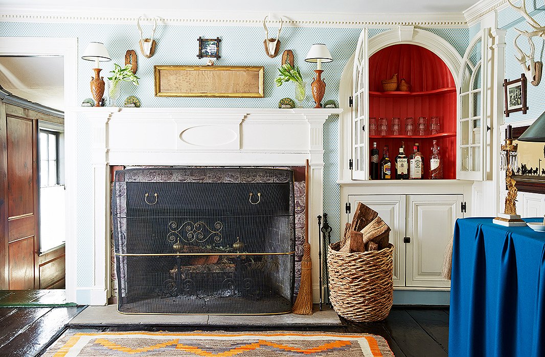 Sky-blue quatrefoil wallpaper beautifully sets off the white molding around the entryway fireplace, one of six in the home.
