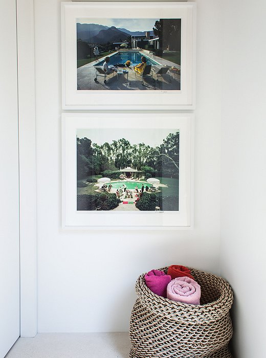 Color photographs by Slim Aarons and a basket of towels—set out to make them easy for guests to grab before hitting the pool—provide striking pops of color in an otherwise subdued home.
