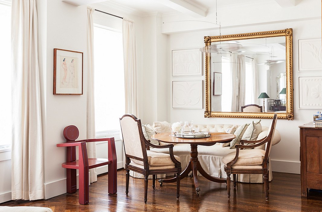 An oversize rectangular mirror is flanked by artwork in the dining area of designer Mariette Himes Gomez‘s home.
