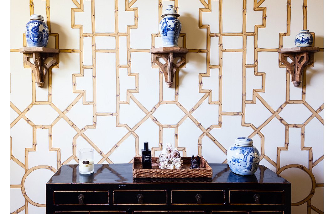 Baldwin Bamboo wallpaper from Scalamandré creates a graphic backdrop to ginger jars resting on brackets.
