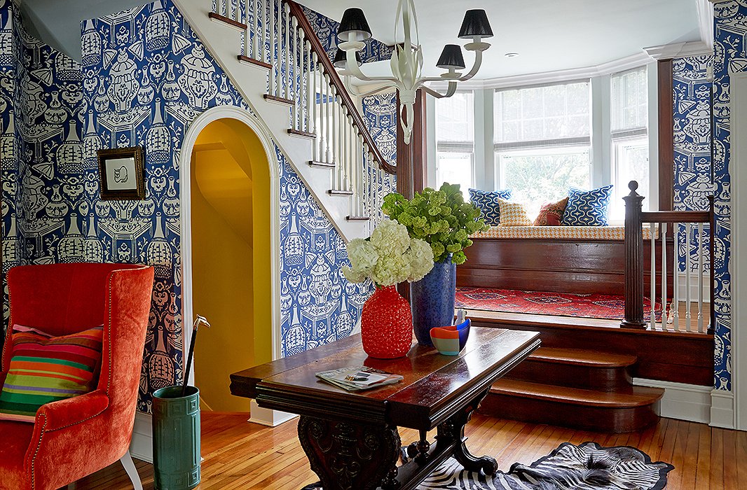 In the entryway, a bright and playful wallpaper by David Hicks gives a sense of lightness to the dark wood trestle table, a family heirloom, and the existing wood detailing.  