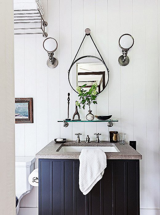 The small round mirror and vintage sconces add vintage charm to the guest bathroom of designer Thom Filicia‘s lake house.
