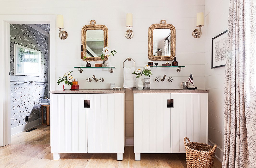 The master bath’s rope-framed mirrors, wood paneling, vintage-inspired hardware, and bare wood floors are a perfect match for the lake house’s old-fashioned, small-town setting.
